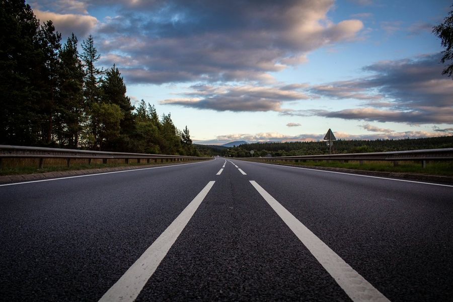 Estrada com faixas brancas e céu com nuvens